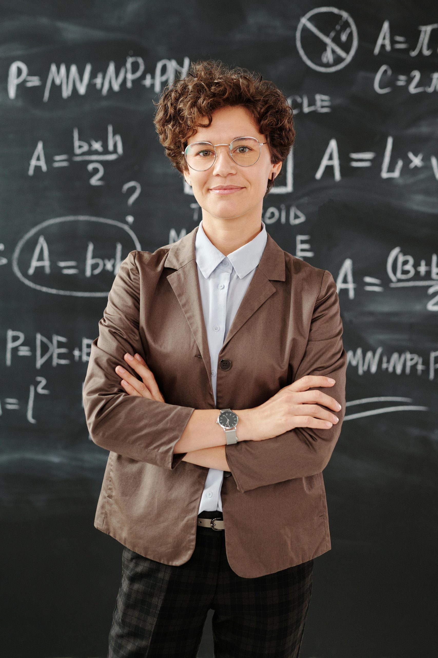 Portrait of a teacher standing in front of a blackboard full of mathematical equations.